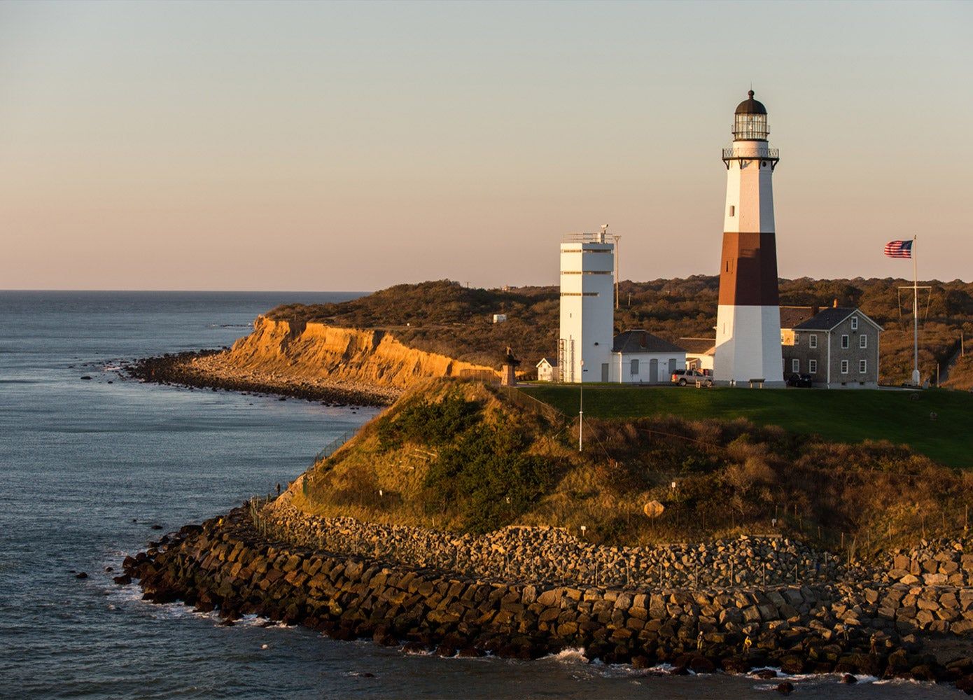 A view of Montauk Lighthouse and the ocean at sunset.
