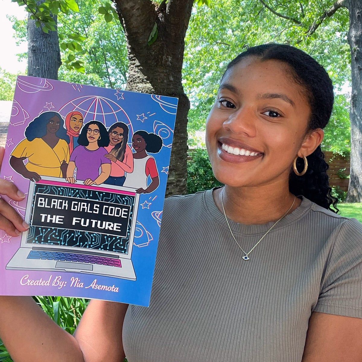 Nia holding Black Girls CODE The Future coloring books while smiling