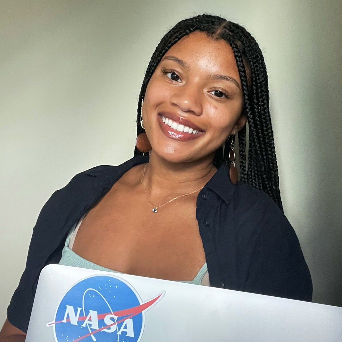 Nia Asemota in front of her laptop with a NASA sticket