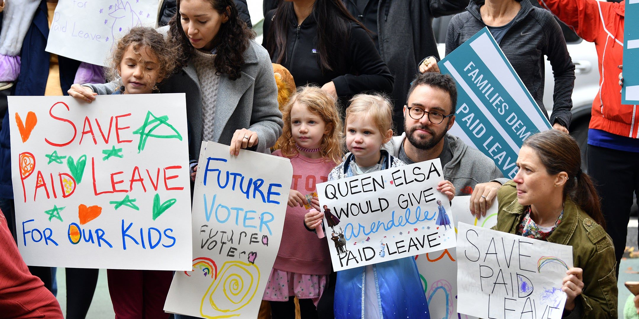 kids and parents with signs supporting paid family leave