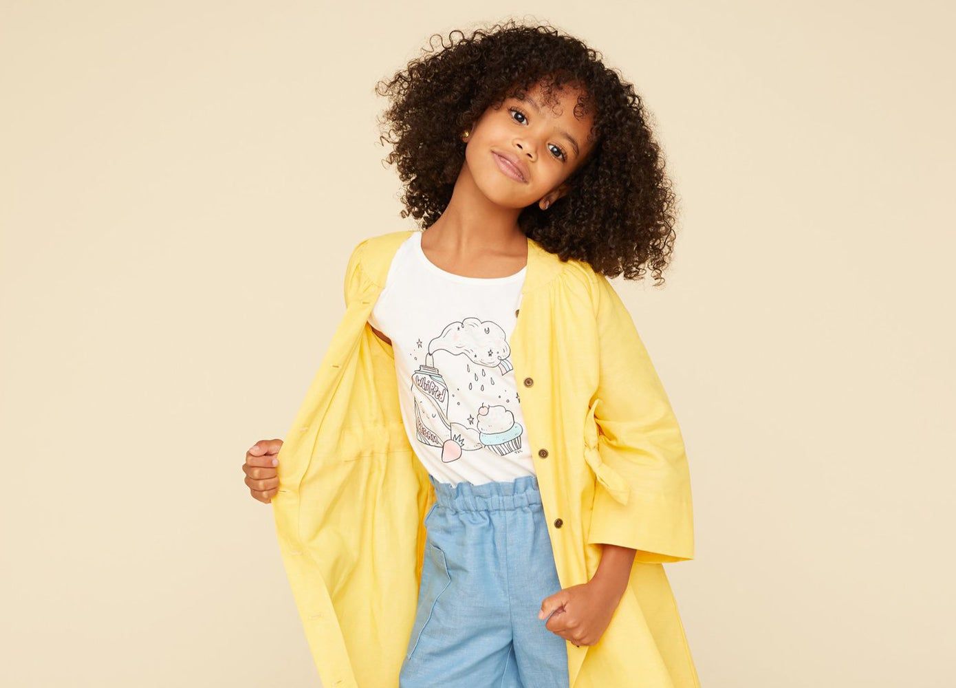 Girl wearing a yellow jacket held open over t-shirt and shorts