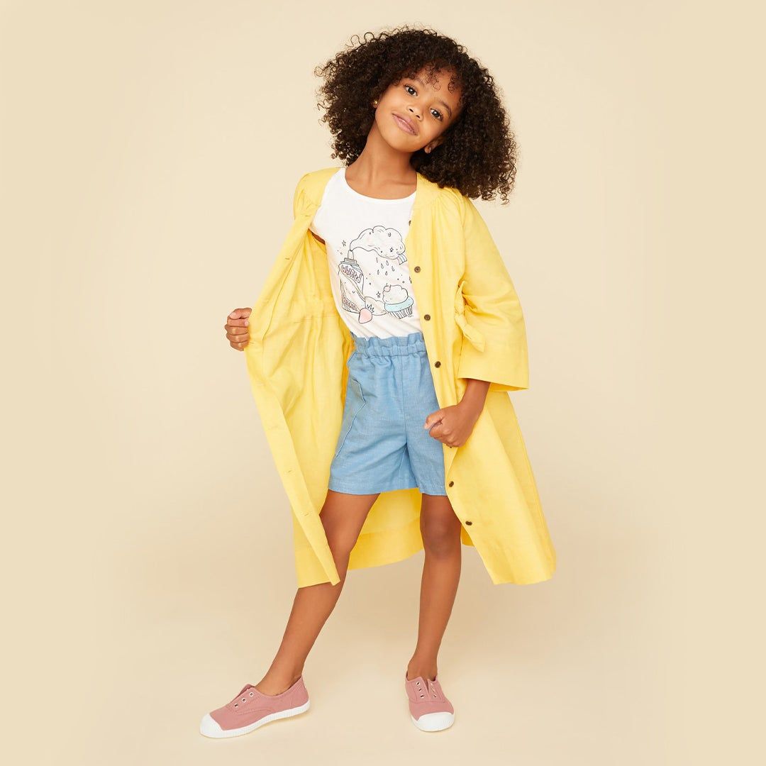 Girl wearing a yellow jacket held open over t-shirt and shorts