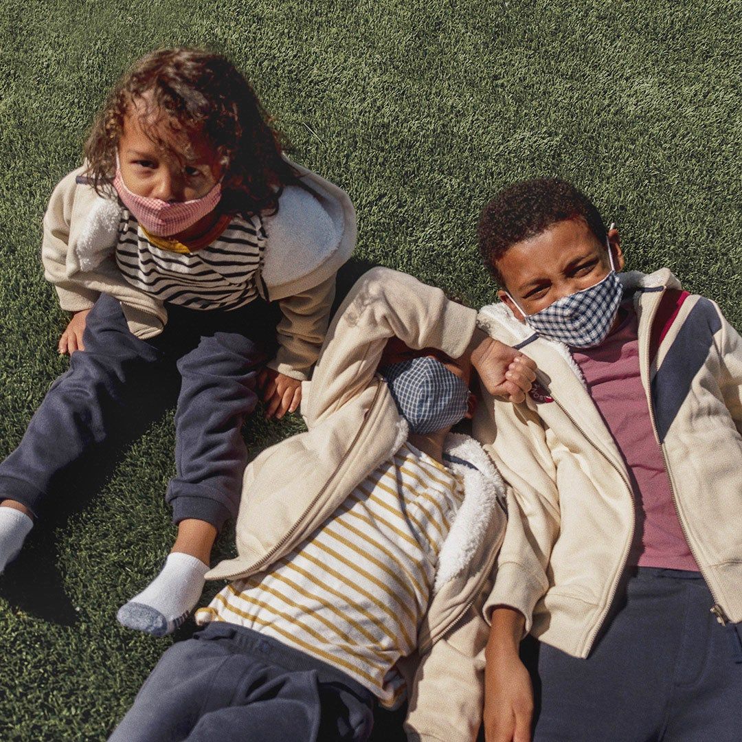Vanessa's three kids wearing masks and lying on the grass