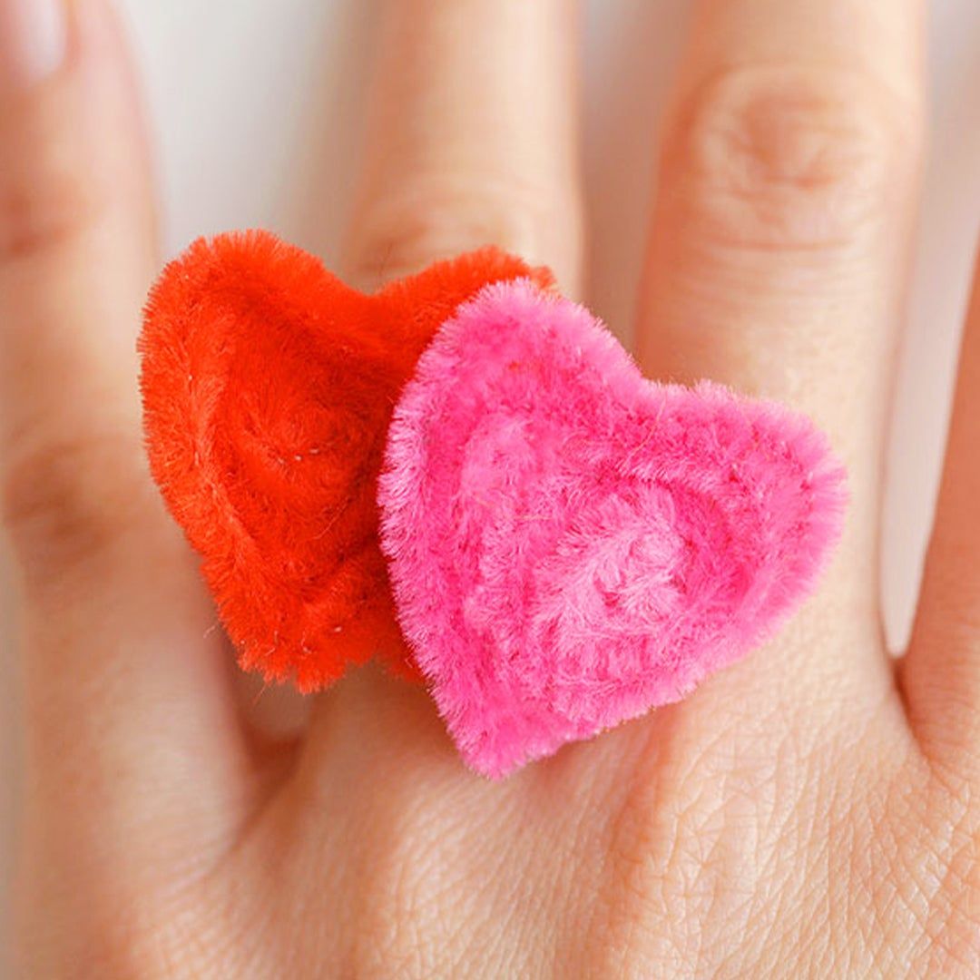 A ring in the shape of two hearts made of red and pink pipe cleaners