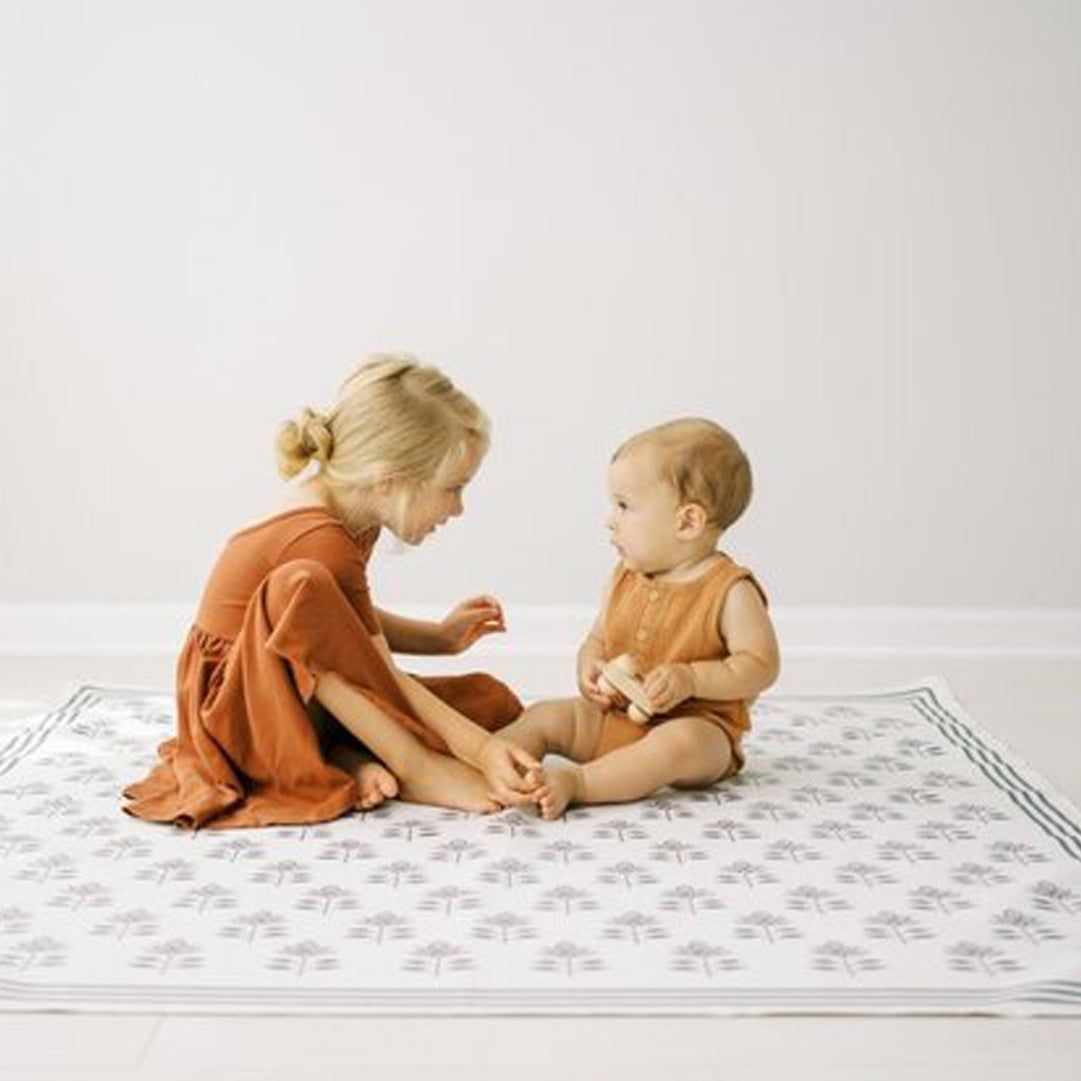 toddler and baby on activity mat for babys first christmas
